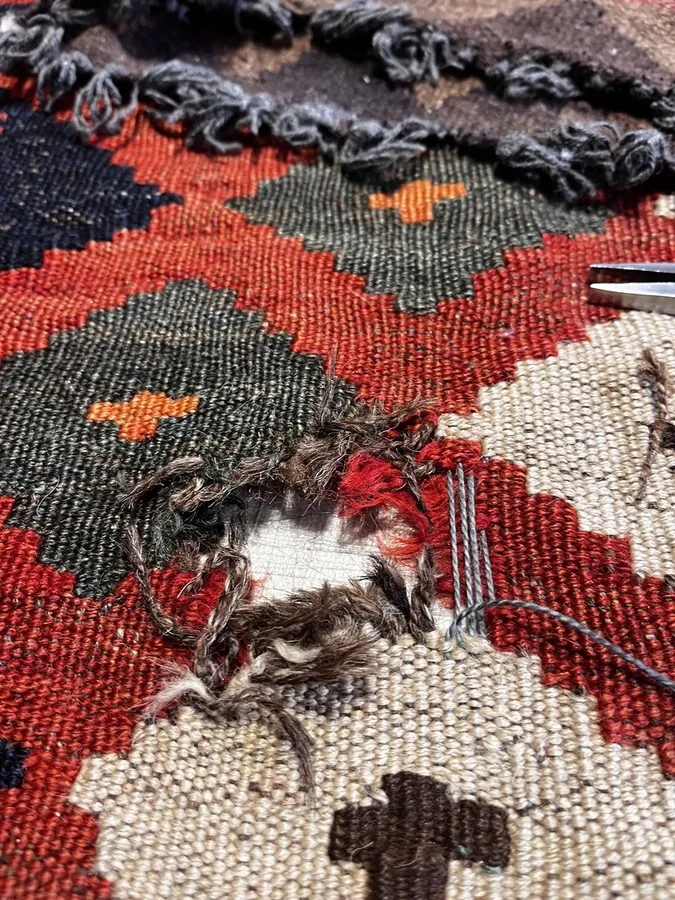 Kilim rug with damaged hole before restoration