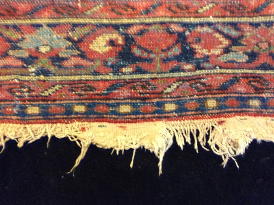 Persian rug with severely frayed and uneven fringe — before restoration